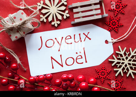 Weihnachtsdekoration wie Geschenk oder Präsent, Schlitten. Karte für Seasons Greetings mit rotem Papier Hintergrund. Französische Text Joyeux Noel bedeutet Frohe Weihnachten Stockfoto