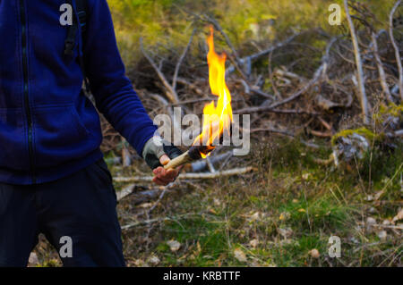 ein Mann und eine Hand mit Fackel Flamme in wilder Natur Hintergrund Teil. Stockfoto