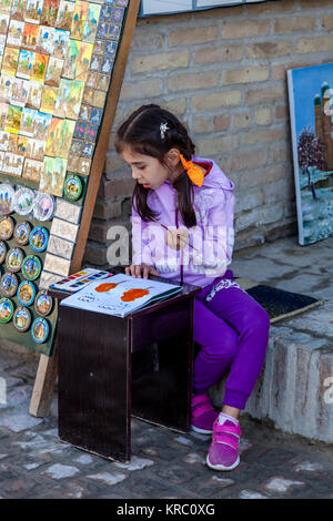 Ein Kind Malerei Bilder auf der Straße, Buchara, Usbekistan Stockfoto