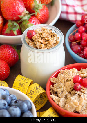 Glas mit frischem Joghurt, Beeren, Müsli und Maßband Stockfoto