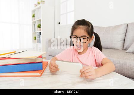 Happy beauty mädchen kinder Schule Hausaufgaben fertig studieren und über Mobiltelefon gerade online lustige Video entspannen. Stockfoto