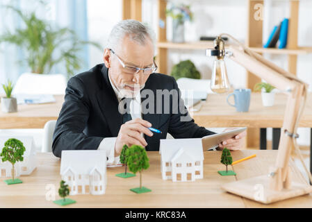 Smart erfahrene Arbeiter an die Miniaturen der Häuser suchen und Denken Stockfoto