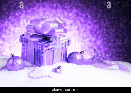 Weihnachten violett Geschenkbox mit Kugeln und Sterne auf Schnee Stockfoto