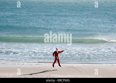 Weihnachtsmann Springen auf den Strand und das Meer im Hintergrund Stockfoto