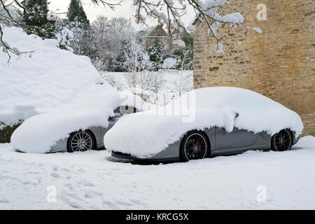 Zwei Porsche im Schnee in einer Einfahrt geparkt. Chedworth, Cotswolds, Gloucestershire, England Stockfoto