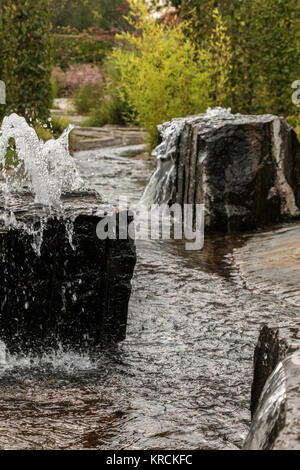 Wasserfontänen aus einem schwarzen Rock im Park Stockfoto