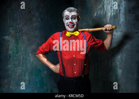 Die beängstigend Clown und Baseballschläger auf Dack Hintergrund. Halloween-Konzept Stockfoto