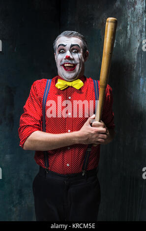 Die beängstigend Clown und Baseballschläger auf Dack Hintergrund. Halloween-Konzept Stockfoto