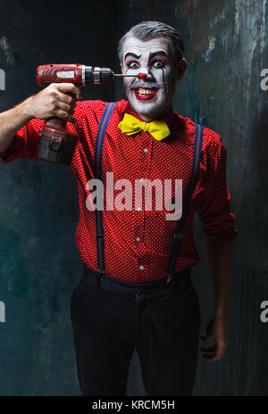 Die beängstigend Clown und Bohrmaschine auf Dack Hintergrund. Halloween-Konzept Stockfoto