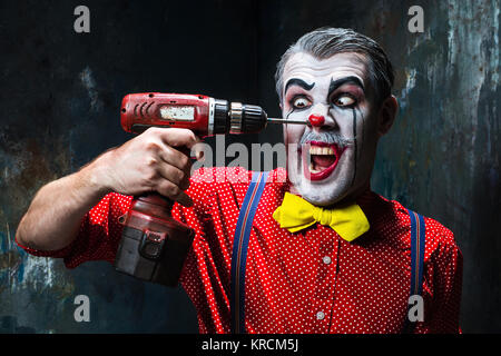 Die beängstigend Clown und Bohrmaschine auf Dack Hintergrund. Halloween-Konzept Stockfoto