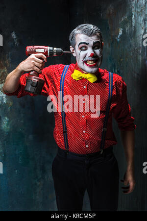 Die beängstigend Clown und Bohrmaschine auf Dack Hintergrund. Halloween-Konzept Stockfoto