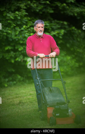 Senior woman Mähen des Rasens in seinem Garten Stockfoto