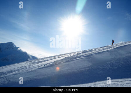 Skifahrer, die in den Hang auf dem Hintergrund der blaue Himmel und die Berge Stockfoto