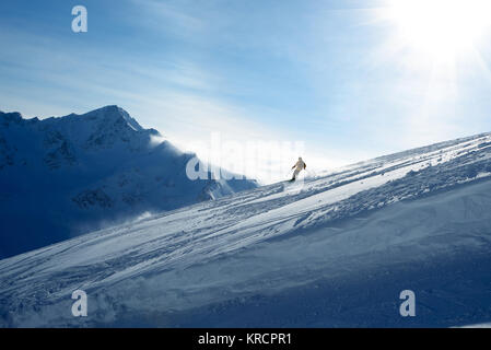 Skifahrer, die in den Hang auf dem Hintergrund der blaue Himmel und die Berge Stockfoto