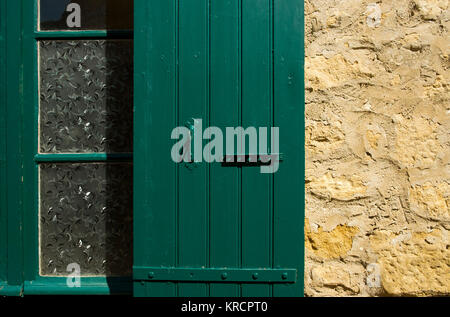 Halb abstrakten grün lackierten Glas Fenster verdeckt und traditionellen Holz- Verschluss in der Dordogne, Frankreich. Stockfoto