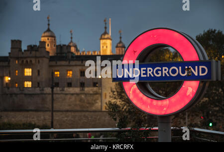 London, Großbritannien, 30. Oktober 2017: Beleuchtete London Underground Logo steht auf Metall Pol in der Nähe des Tower von London bei Nacht Stockfoto