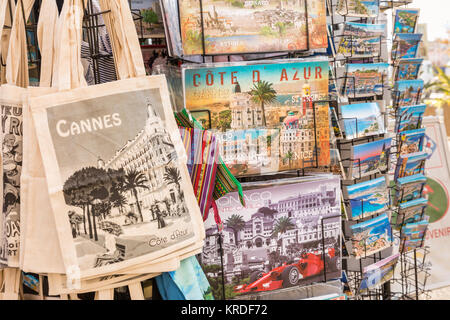Dekorative touristische Taschen, Bilder und Postkarten auf Anzeige an einem Souvenir stall in Cannes, Côte d'Azur, Südfrankreich Stockfoto