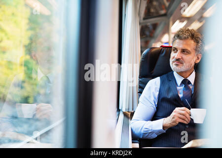 Reifen Geschäftsmann mit Kaffee, der mit dem Zug reist. Stockfoto