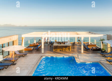 Luxuriöse Pool und eine Lounge mit Bar, mit Blick auf den tropischen Ozean während der Goldenen Stunde - in Rio de Janeiro, Brasilien erfasst Stockfoto