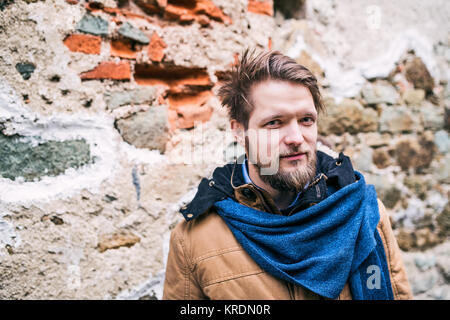 Ein junger Hippie Mann gegen eine alte Mauer stehen. Stockfoto