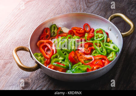 Grünen und roten Pfeffer braten in einer Pfanne Stockfoto