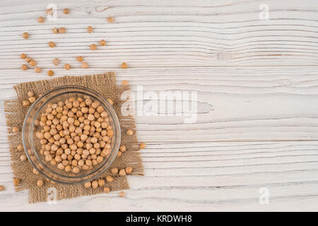 Kichererbsen in eine Glasschüssel auf dem alten Holztisch. Stockfoto