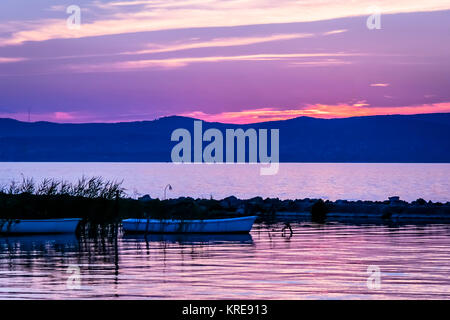 Vivid pink Sonnenaufgang über ruhige See und die Silhouette von Ruderbooten. Bunte sunrise mit kleinen Booten an der ruhigen See Balaton, Ungarn. Stockfoto