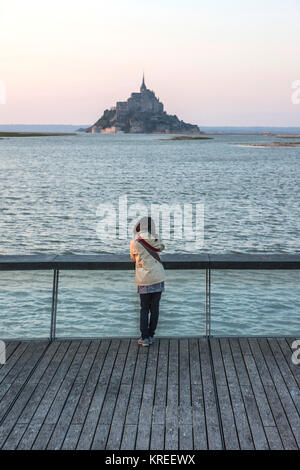 Mont Saint-Michel (St. Michael's Mount), Normandie, Nord-westlichen Frankreich: Frau, japanische Touristen von hinten Blick auf Le Mont Saint-Michel gesehen Stockfoto