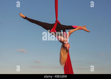 Eine akrobatische Tricks auf einer Hängematte hoch in den Himmel, eine Frau, die Antenne Acrobat. Stockfoto