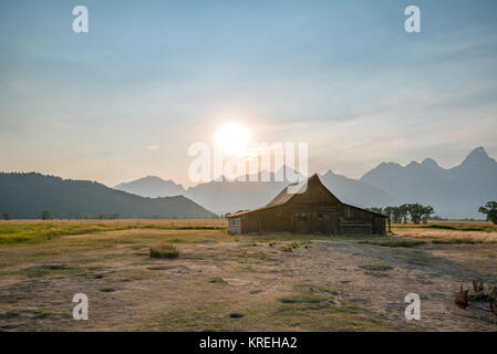 Die untergehende Sonne taucht über Teton Bergkette und historischen T.A Molton Scheune auf Mormon Reihe, Grand Tetons National Park, Teton County, Wyoming Stockfoto