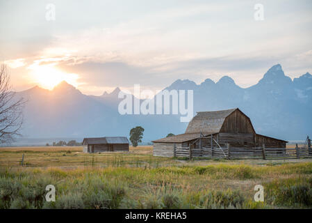 Die untergehende Sonne taucht über Teton Bergkette und historischen John moulton Scheune auf Mormon Reihe, Grand Tetons National Park, Teton County, Wyoming Stockfoto