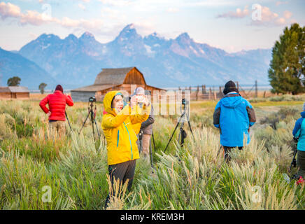 Asiatische Frau nimmt Fotos mit ihr Telefon vor John moulton Scheune und Teton Bergkette, Grand Tetons National Park Stockfoto