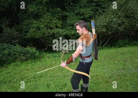 â Â Â Â junger mittelalterlicher Bogenschütze mit Kettenpost, Bogen und Pfeil in der Natur beim Verbeugen Stockfoto