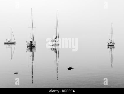 Eindrucksvolle Bilder von yatchts im Nebel auf Windermere auf einer sehr ruhigen Dezember Morgen Stockfoto