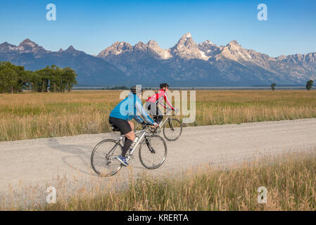 Zwei Radfahrer Fahrt entlang einer Schotterstraße mit Teton Bergkette im Hintergrund, Grand Tetons National Park, Teton County, Wyoming Stockfoto