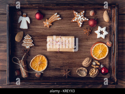 Weihnachten Geschenk, dekorierte Lebkuchen Kekse, gebratene orange Scheiben, Muttern, Zimt, Anis auf Holz Fach über dem alten Holztisch, von festlich dekoriert d Stockfoto