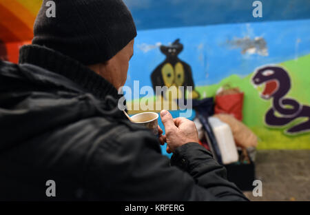 Ein Obdachloser, der in einer Fußgängerunterführung lebt, erhält Tee von Freiwilligen des Vereins "Kaeltebus Muenchen" (Lit. München Winter Bus) in München, Deutschland, 03. Dezember 2017. Foto: Andreas Gebert/dpa Stockfoto