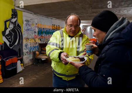 München, Deutschland. 03 Dez, 2017. Berthold Troitsch (L), Gründer des Vereins "Kaeltebus Muenchen" (Lit. München Winter Bus), die eine warme Mahlzeit zu einem Obdachlosen Mann, der in einer Fußgängerunterführung in München, Deutschland, 03. Dezember 2017 lebt. Credit: Andreas Gebert/dpa/Alamy leben Nachrichten Stockfoto