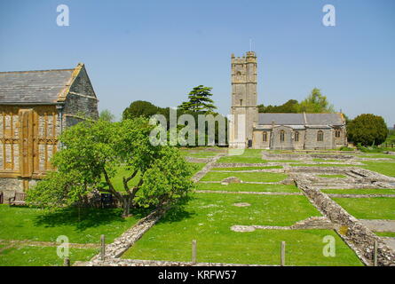 Blick auf Muchelney Abbey (links), ein denkmalgeschütztes Gebäude der Kategorie I im Dorf Muchelney, Somerset, mit der Pfarrkirche St. Peter und St. Paul in der Ferne auf der rechten Seite. Blick über die ausgegrabenen Überreste der Abtei aus dem Mittelalter. Stockfoto