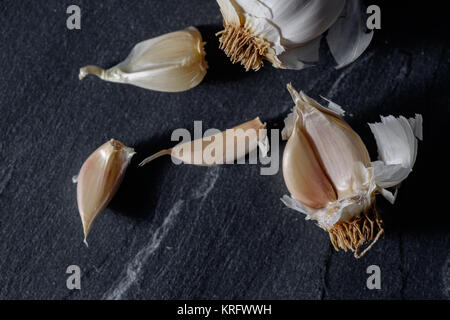 Knoblauchzehen closeup Makro kommerziellen studio Bild auf dunkelgrau oder schwarz Granit Hintergrund. Stockfoto