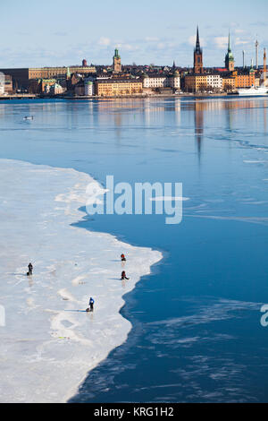 Eisfischen auf dem zugefrorenen Bucht Riddarfjärden, Mälaren. Der Hintergrund Riddarholmen und die berühmten riddarholmen Kirche Stockfoto