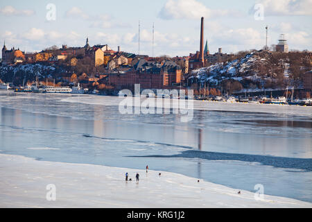 Eisfischen auf dem zugefrorenen Bucht Riddarfjärden, Mälaren. Die Ansicht im Hintergrund zeigt Söder Mälastrand, Södermalm. Stockfoto