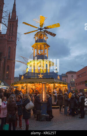 Menschen stehen um einen Glühwein stand mit einer großen Pyramide. Die Marktkirche (Marktkirche) kann im Hintergrund gesehen werden. Th Stockfoto