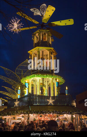 Menschen stehen um einen Glühwein stand mit einer großen Pyramide. Die Twinkling Star Weihnachtsmarkt in Wiesbaden, Deutschland wird gehalten Stockfoto