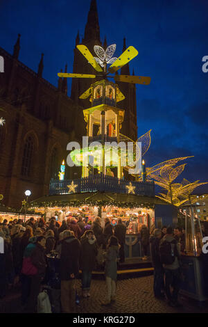 Menschen stehen um einen Glühwein stand mit einer großen Pyramide. Die Marktkirche (Marktkirche) kann im Hintergrund gesehen werden. Th Stockfoto