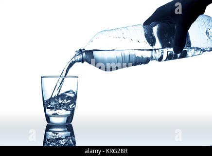 Hand gießt Wasser aus Kunststoff Flasche in ein Glas Stockfoto