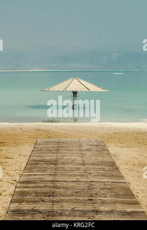 Einem Dach im Wasser des Toten Meeres vor dem Strand mit Holzbohlen weg. Stockfoto