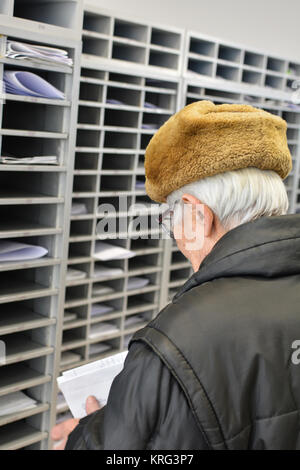 Active Senior in einem Post, seine E-Mails überprüfen, der finanzielle Bericht aus einer Bank Stockfoto