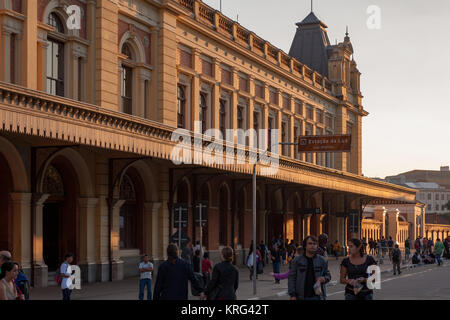 Menschen zu Fuß und Kreuzung Straße neben Estacao da Luz (Luz) Bahnhof bei Sonnenuntergang, Sao Paulo, Brasilien Stockfoto