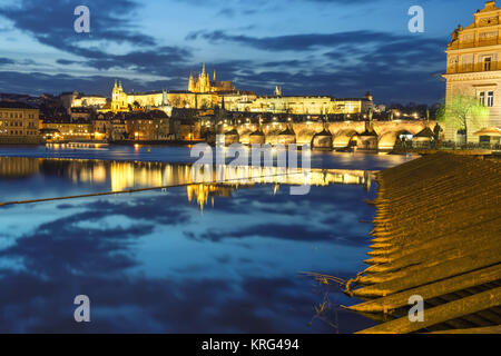 Die Prager Burg mit den umliegenden Gebäuden im Fluss in der Nacht wider Stockfoto